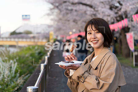 花見で食べ物を食べる女性 正面を見る a0050708PH