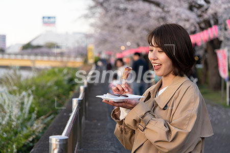 花見で田楽を食べるスプリングコートを着た女性 手元を見る a0050709PH