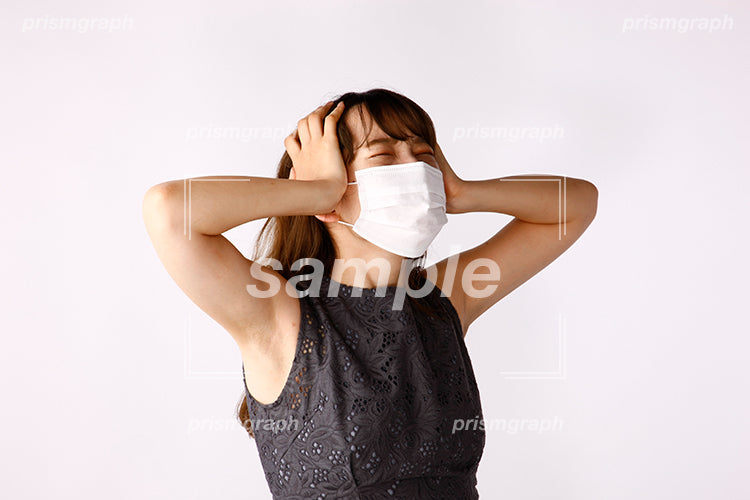 頭を抱えて目を閉じて苦悩するマスクの女性 ak080049