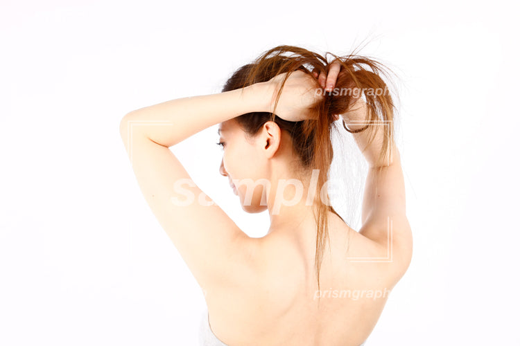 髪の毛を束ねようとして後ろ髪を触る女性 aq0090036