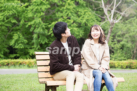 公園のベンチに腰掛けて空を気にしている夫婦 ay0060083PH