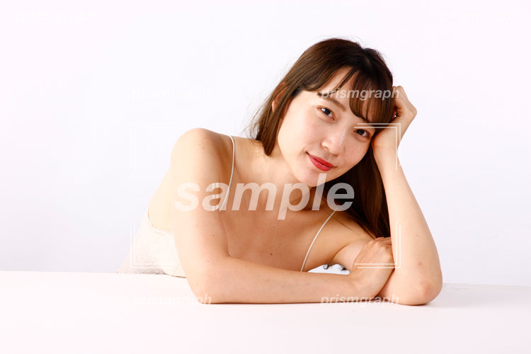 手を組んで頭にあてながら座っている白いキャミソールの女性 ay0080144