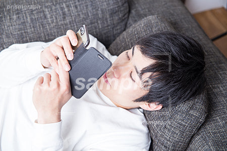 ソファーで携帯を見る男性 az0060131PH
